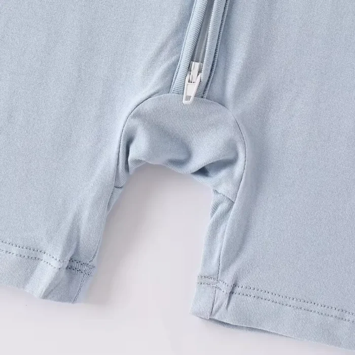 Close-up of baby romper crotch zipper, featuring a convenient two-way or bottom-access zip for easy diaper changes and soft-stretch cotton jersey fabric. High-quality infant apparel functionality from a professional clothing manufacturer.