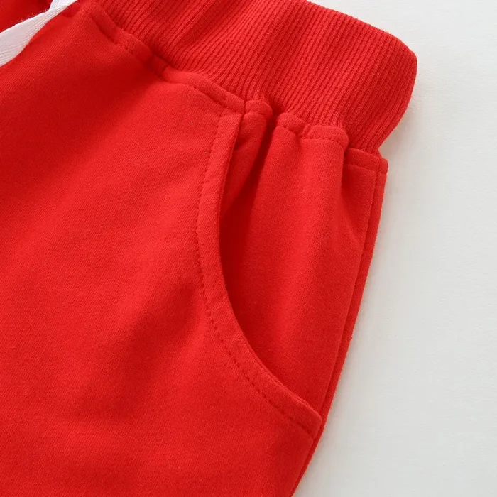 Close-up of baby red shorts detail, featuring a thick ribbed elastic waistband, precision-stitched side pocket, and premium vibrant cotton fabric. High-quality infant apparel construction from a professional clothing manufacturer.