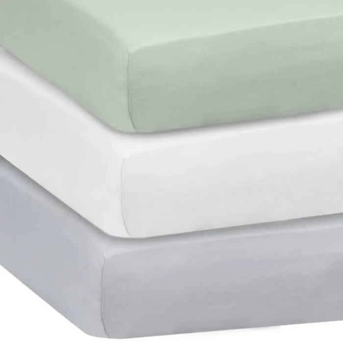 Stack of solid color crib sheets in sage green, white, and gray from an OEM crib sheets factory in China.