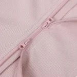 Close-up of a high-quality two-way zipper on a pink baby romper, showcasing smooth sliding functionality and tonal matching color. Essential functional infant sleepwear hardware from a professional clothing manufacturer.