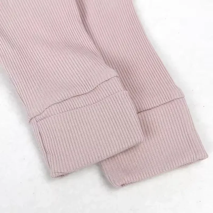 Close-up of baby romper ribbed cuffs, featuring high-stretch premium pink ribbed fabric and durable flat-lock stitching. High-quality infant apparel finishing details from a professional clothing manufacturer.